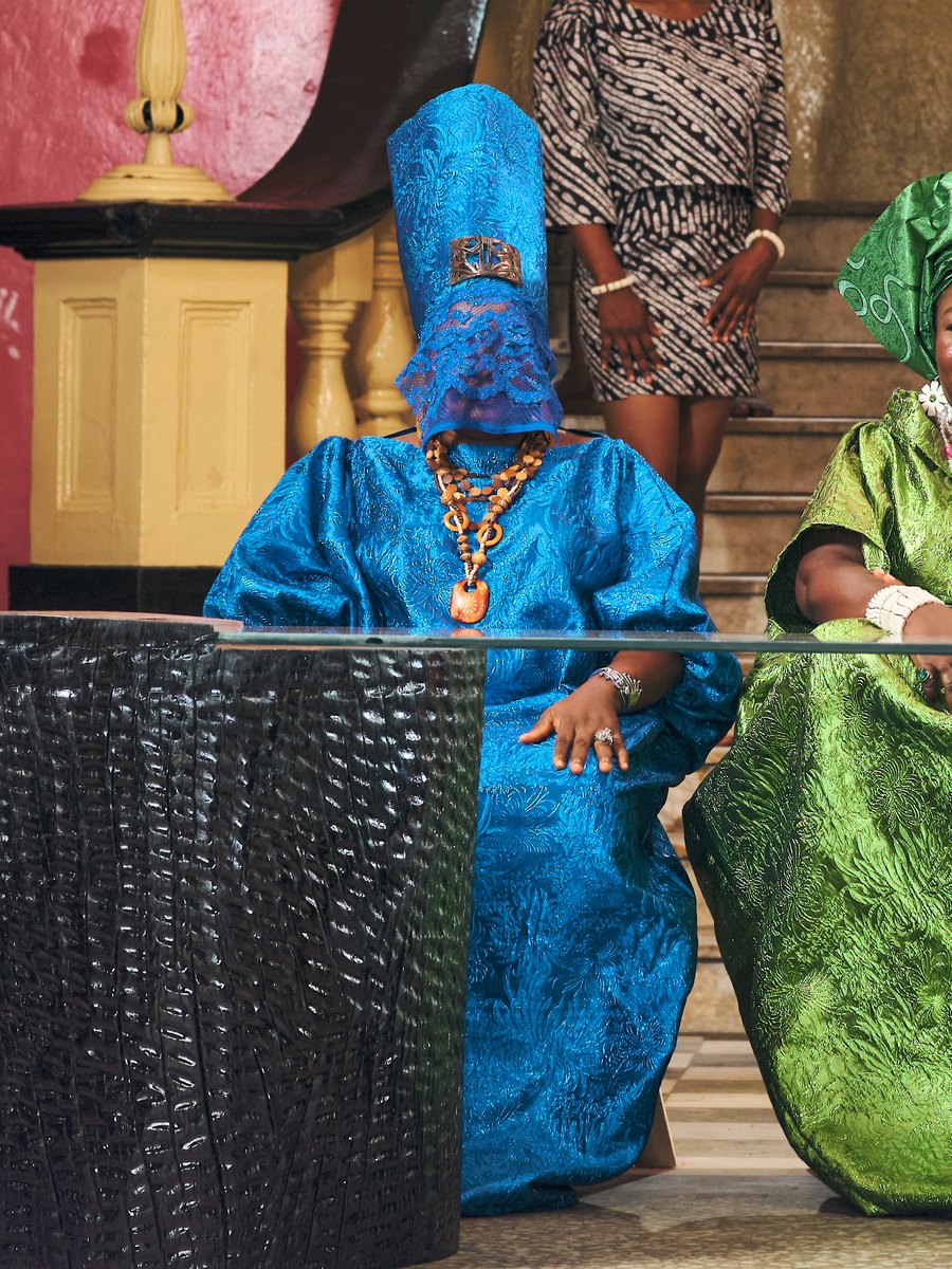 A keeper in blue, her face veiled, seated at the table