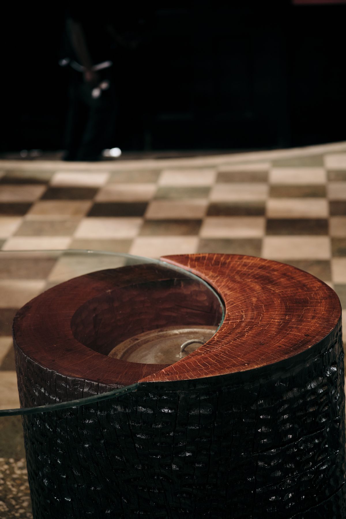 Looking down into the round base: the lidded pot held inside the reddish wood, beneath the glass